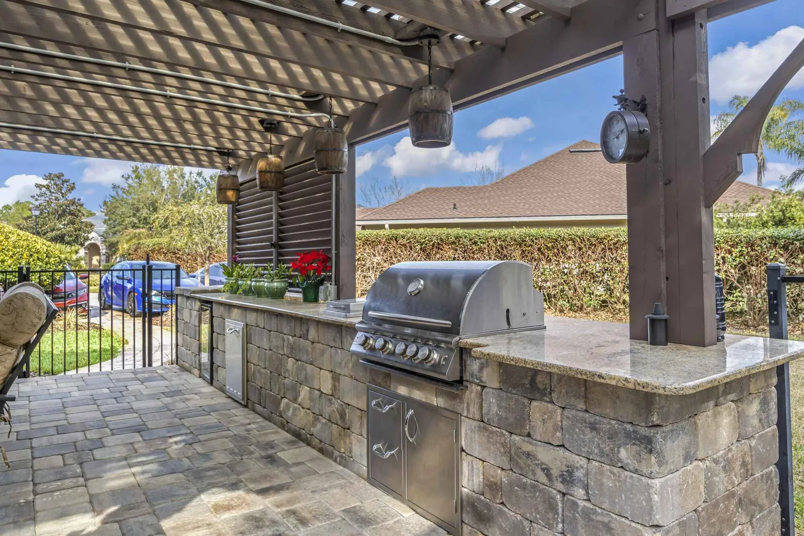 Custom outdoor kitchen under a pergola with a paver patio