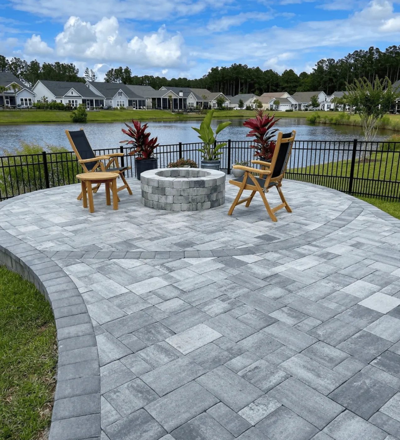 Circular paver patio with a stone fire pit by the water